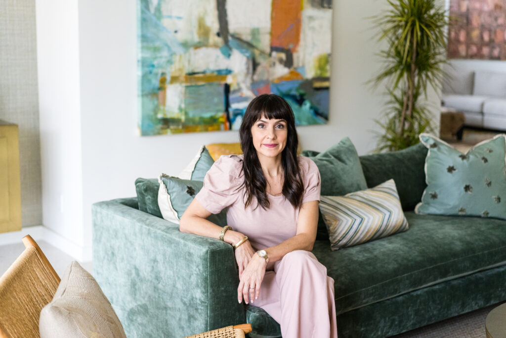 Woman sitting on a green couch, posing for new branding photos with a branding photographer in Austin, Texas