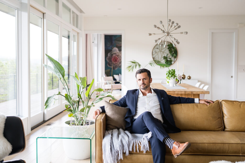 Business man sitting on a brown leather couch, posing for new branding photos in Austin, Texas