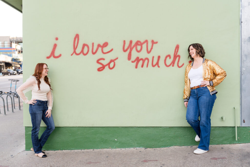 Small business owners laugh by the I Love You So Much sign at Jo's Coffee Shop in Austin, TX