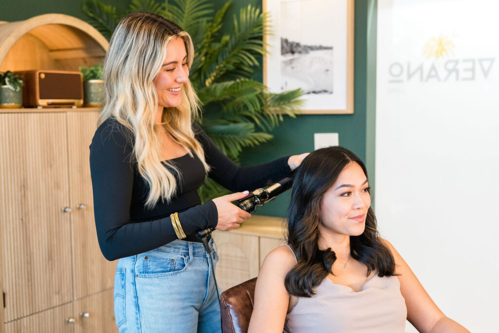 Hair stylist curling a client's hair in a private salon suite at Verano Luxe in the Austin Texas area