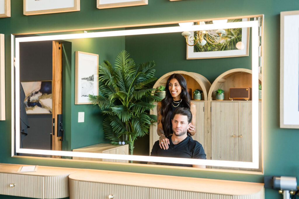 Mirror reflection of a hair stylist and male client inside the green private salon suite at Verano Luxe near Austin Texas
