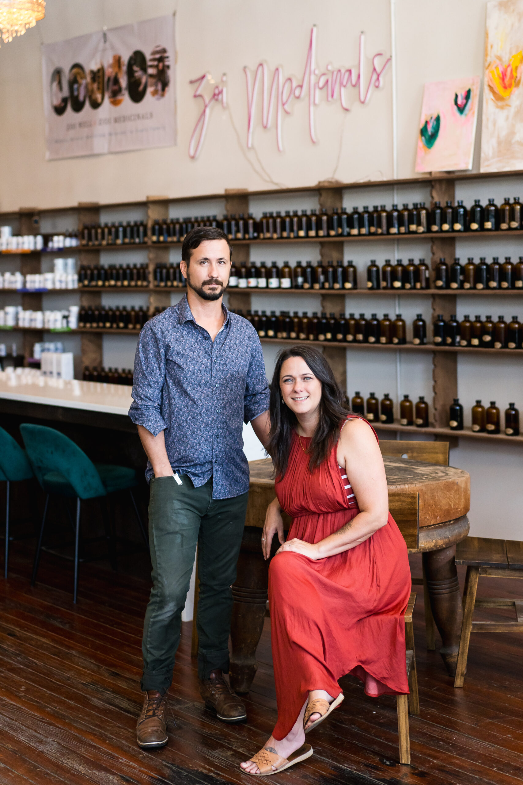 a man and a woman sitting in front of a display of natural medicine bottles