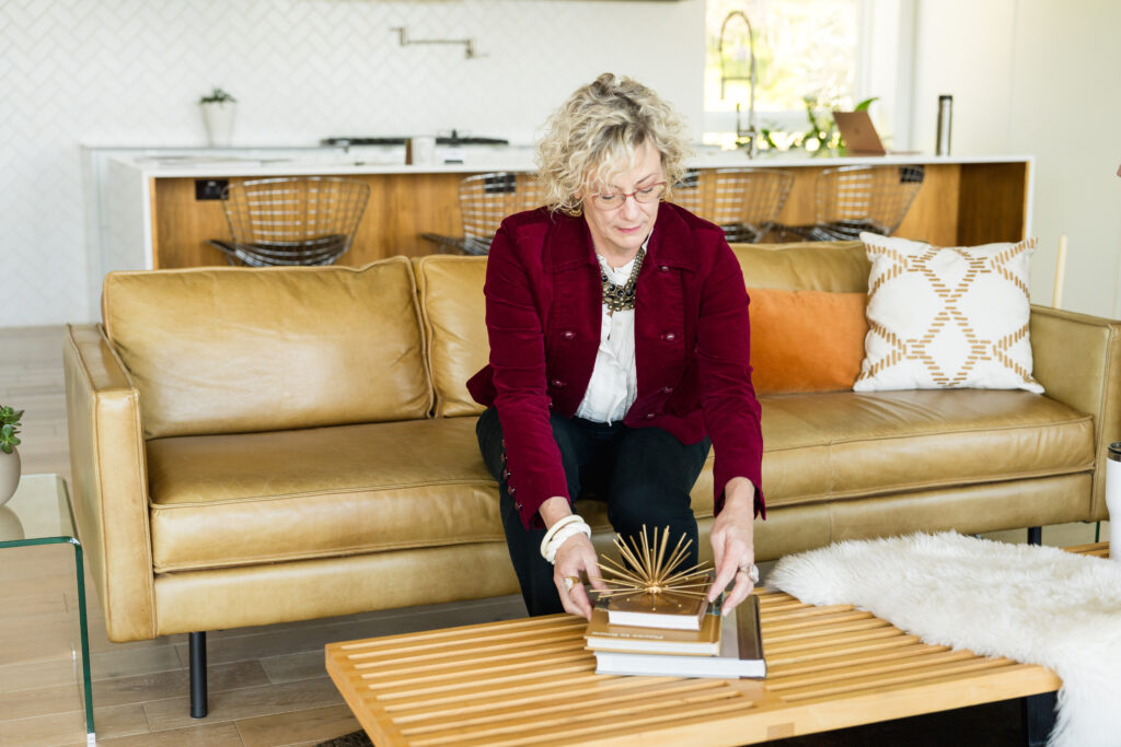 a woman fixing books on a coffee table during a brand photo session
