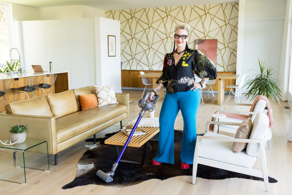 a woman in colorful clothes vacuuming the floor during a brand photo session