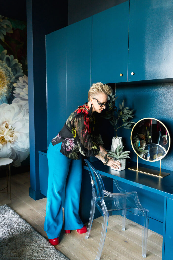 a woman straightening a plant on a blue built in desk unit during a brand photo session